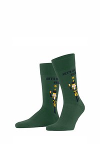 Zielone bawełniane skarpety z motywem dziadka do orzechów, z napisem "ZALEŻY NAM NA ORZECHACH" nadrukowanym powyżej. Gładka struktura z prążkowanymi mankietami.