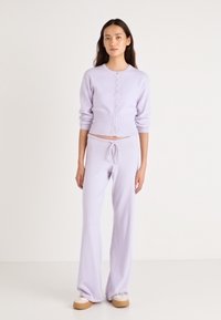 Σετ πλεκτών σε λιλά απόχρωση που περιλαμβάνει ένα ζακέτα με κουμπιά και παντελόνι με κορδόνι και χαλαρή εφαρμογή. Μαλακή υφή και ριμπ λεπτομέρειες σε όλο το σύνολο.