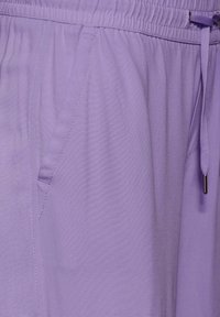 Fioletowy, lekki materiał z elastyczną talią, sznurkiem do regulacji i bocznymi kieszeniami. Gładka tekstura z delikatnym połyskiem.