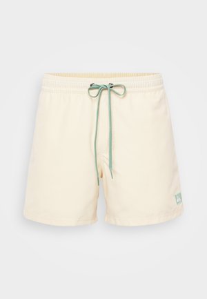 Shorts de bain crème clair avec une taille élastique, un cordon de serrage vert menthe et un petit logo cousu en bas. Matériau lisse et léger.