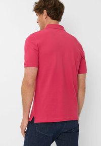 Różowa koszulka polo z krótkim rękawem, z bocznymi rozcięciami, wykonana z mieszanki bawełny, z widocznymi szwami i klasycznym wzorem kołnierzyka.