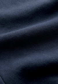 Ciemnotkaninowy granatowy materiał o gładkiej fakturze i subtelnych skośnych splotach, prezentujący miękkie, ciasno utkane wzory tkaniny.