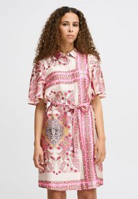 Rochie cu mânecă scurtă și guler din țesătură roz deschis. Prezintă modele paisley și flori în nuanțe de roz, aur și negru, cu un cordon în talie.