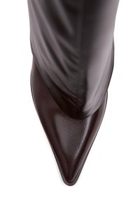 Knähög brun läderstiletto stövel med spetsig tå, med en slät ytstruktur och en elegant design. Diskret sömdetalj nära toppen.