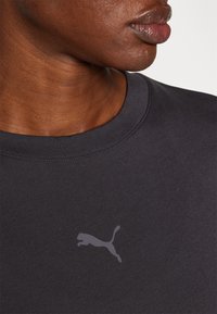 Mørk grå T-skjorte laget av bomullsblanding, med en liten reflektiv Puma-logo på brystet og en rund halsdesign.