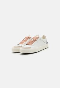 Sneakers brancos em couro com atacadores rosa claro, detalhes em camurça bege e um calcanhar cinza texturizado. Apresenta uma sola grossa e texturizada.