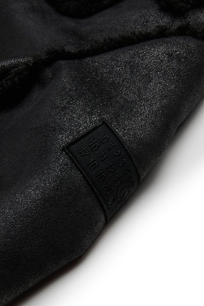 Produto em pele texturada preta com um interior suave e um rótulo preto em relevo com números e um logótipo circular.