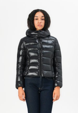 Zwarte pufferjack met een hoge kraag, glanzend materiaal, horizontale naden en een rits aan de voorkant. Gemaakt met donkere jeans.