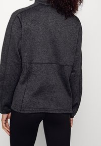 Czarny szary pulower z miękkiej dzianiny, z wysokim kołnierzem, raglanowymi rękawami i szwem na górze pleców. Prosty, minimalistyczny design.