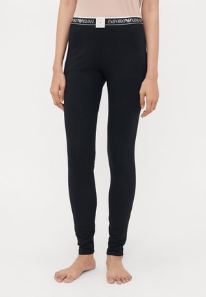 Zwarte leggings van zachte stof met een strakke pasvorm. Heeft een witte tailleband met het "Emporio Armani"-logo prominent weergegeven.