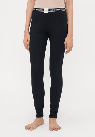 Czarne legginsy wykonane z miękkiej tkaniny o dopasowanym kroju. Posiadają białą talię z wyraźnie wyeksponowanym logo "Emporio Armani".