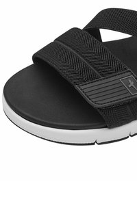 Chanclas negras con tiras de tela texturizada, suela de goma blanca y un detalle con el logo en la tira.