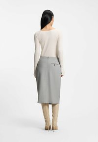 Light gray pencil skirt with back vent, two rear pockets, and subtle texture, paired with a fitted beige long-sleeve top and tall beige boots.