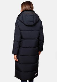 Long black puffer coat with a hood, featuring horizontal stitching and a faux fur accent at the collar. Zipper pocket detail visible.