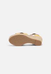 Yellow wedge sandal with a braided jute midsole, textured rubber outsole, and adjustable leather strap detail.