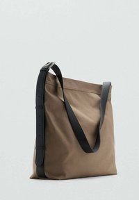 Bolsa de lona en marrón con una correa de cuero negro, que presenta un diseño minimalista y forma rectangular. Textura suave y construcción resistente.