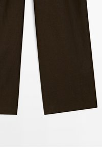 Jambes de pantalon en tissu marron foncé à coupe droite sur fond blanc, ne montrant que la partie inférieure du pantalon.