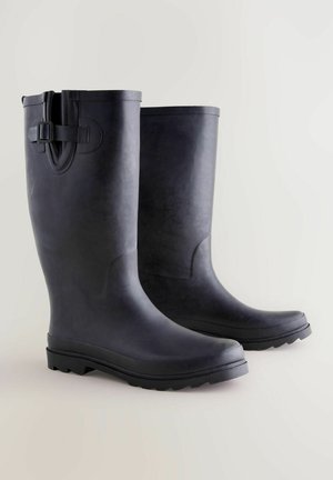 Czarne gumowe kalosze o gładkiej fakturze, zaokrąglonym czubku, podwyższonej pięcie i regulowanym zapięciu na górze. Podeszwa z bieżnikiem zapewniająca przyczepność.