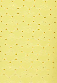 Gult tyg med ett intrikat, upprepat mönster av blommor och scallopformade former med små urklippta hål och kontrasterande detaljer.