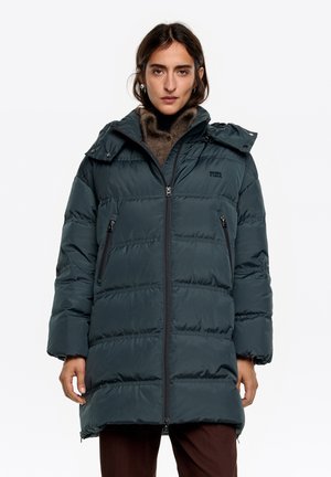 Długa, pikowana kurtka w ciemnozielonym kolorze, z zamkiem błyskawicznym, bocznymi kieszeniami oraz odpinanym kapturem o gładkim, błyszczącym wykończeniu.