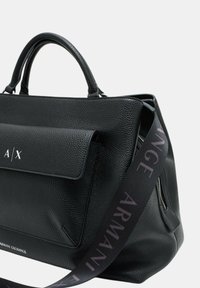 Borsa a tracolla nera in pelle textured con patta frontale, con il logo "A/X". Include una tracolla in tessuto con "ARMANI EXCHANGE" stampato in viola chiaro.