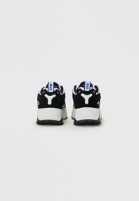 Pair of black and white sneakers shown from the back with blue and white pull tabs and thick white soles on a plain background.