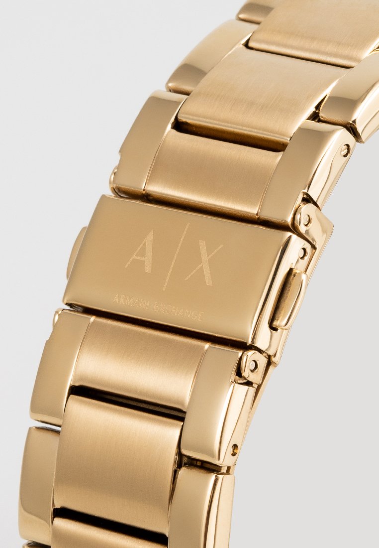 Pulsera de reloj de acero inoxidable en tono dorado con acabado pulido y cepillado, que presenta el logo grabado de A/X y un diseño de cierre seguro.