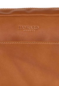 Brun lærpung med preget "HOWARD LONDON"-logo, glatt tekstur og sømmet kanter. Enkel design, rektangulær form.