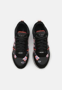 Černé tenisky s květinovým vzorem v červené, modré a bílé barvě, vybavené černými tkaničkami, stříbrným akcentem a texturovanou podrážkou.