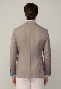 Blazer en lin beige, tissu textur�é, fente simple, revers crantés, deux poches avant, associé à une chemise bleu clair aux poignets.