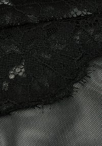 Tissu en dentelle noire arborant des motifs floraux avec des détails complexes et un arrière-plan en maille lisse et translucide, mettant en valeur des textures délicates.