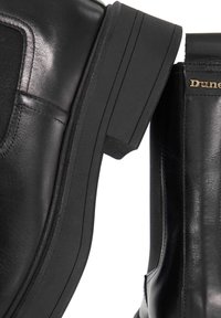 Zwarte leren Chelsea-boots met elastische zijden en forse zolen, voorzien van gouden merkletters op het bovenste deel van de hiel.