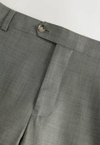 Light gray trousers featuring a flat front, zip fly, and a button closure, made from a textured fabric with subtle diagonal stripes.