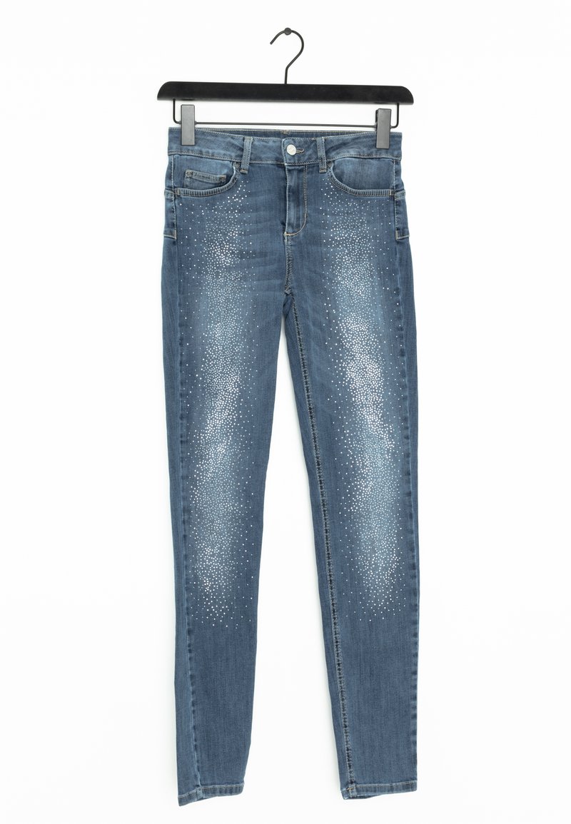 Jean en denim bleu skinny avec une finition délavée, présentant des embellissements en clous argentés disposés en motif dégradé sur le devant.