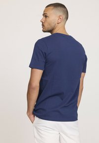 T-shirt bleu marine à manches courtes en tissu doux, avec un col rond, une texture lisse et une silhouette ajustée. Vue arrière unie.