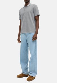 Grå kortærmet polo-shirt med struktureret overflade, parret med lyseblå brede jeans og brune slip-on sko.