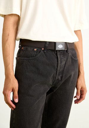 Sorte denim jeans med forlommer, kobbernitter og et vævet mørkebrunt bælte med en sølvfarvet logo-spænde. Casual pasform og struktur synlig.