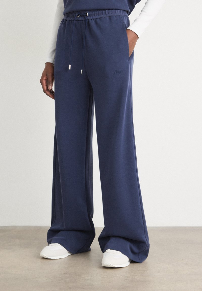 Pantaloni sportivi larghi navy in morbido tessuto, con cintura elastica e cordino, tasche laterali e minimo dettaglio di branding.