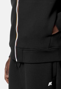 Sort zip-up hættetrøje lavet af en bomuldsblanding. Har kontrasterende lynlåsdetaljer og ribbede manchetter. Dertil sidelommer. Enkelt design.