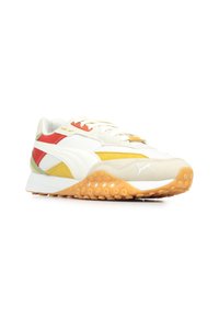 Sneakers che presentano una combinazione di colori crema, giallo, rosso e verde. Parte superiore in tessuto testurizzato con una suola in gomma arancione ammortizzata.
