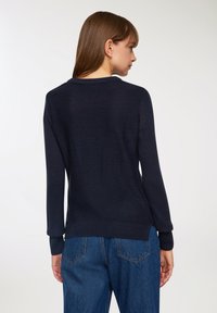 Granatowy sweter z dzianiny z okrągłym dekoltem, długimi rękawami i prążkowanymi mankietami. Miękka tekstura, dopasowane wykończenie i prosty design.