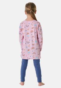 Rosa Langarmshirt mit Regenbogen- und Wolkenmustern, kombiniert mit blauen Leggings. Aus Baumwollmaterial mit lockerer Passform. Weicher Stoff ist deutlich spürbar.