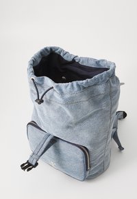 Denim húzózsinóros hátizsák, összegyűjtött tetejével és elülső cipzáras zsebével, kék szövetből készült, diszkrét varrással és állítható pántokkal.