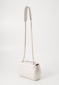 Bolso de mano acolchado en crema con un acabado mate, que cuenta con una cadena dorada como asa y un diseño estructurado. Incluye cierre de solapa y opciones de doble correa.