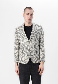 Blazer z ľahkej tkaniny s čierno-bielym hadím vzorom, s jediným gombíkom a klopami. Dlhé rukávy.