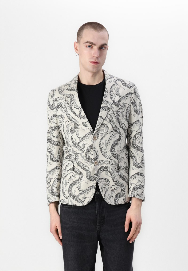 Blazer z ľahkej tkaniny s čierno-bielym hadím vzorom, s jediným gombíkom a klopami. Dlhé rukávy.