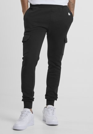 Zwarte cargojoggers met taps toelopende benen, voorzien van twee zijzakken. Draag ze met witte sneakers en een eenvoudig wit T-shirt. Zachte, rekbare stof.