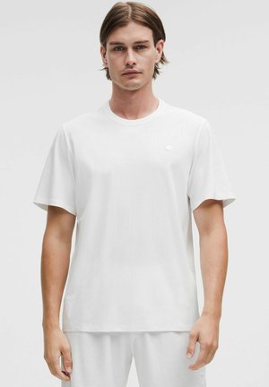 Vit kortärmad T-shirt med rund halsringning, som har en subtil textur. Litet logobehov på vänster bröst. Lättviktig tyg.