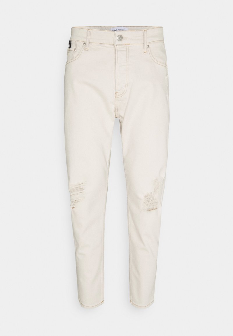 Světle béžové džíny z denimu s opranými detaily, pěti kapsami, zapínáním na knoflík a tapered střihem. Hladká textura s jemným leskem.