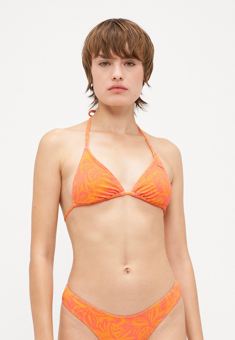Ljust orange bikini-set med en triangulär topp och matchande botten som har ett bladmönster och tunna band. Slät tygstruktur.